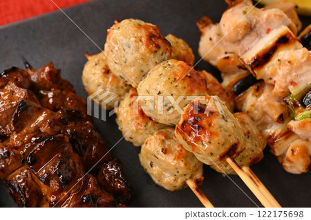 Yakitori (grilled chicken) dishes arranged on a long plate, garnished with sauce, salt, scallions, meatballs, liver, and lemon. Yakitori (grilled chicken) dishes arranged on a long plate, garnished with sauce, salt, scallions, meatballs, liver, and lemon. 122175698