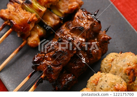 Yakitori (grilled chicken) dishes arranged on a long plate, garnished with sauce, salt, scallions, meatballs, liver, and lemon. Yakitori (grilled chicken) dishes arranged on a long plate, garnished with sauce, salt, scallions, meatballs, liver, and lemon. 122175700