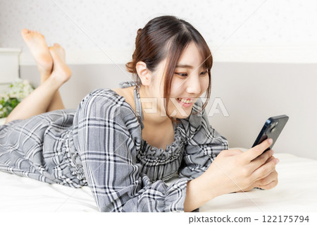 A woman relaxing in a room with a smartphone 122175794