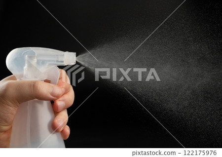 Close up of bottle in hand with spray cloud 122175976