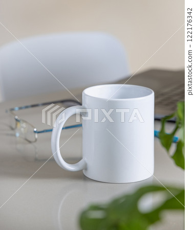 White coffee mug on grey office table against laptop, glasses and plant closeup, mockup White coffee mug on grey office table against laptop, glasses and plant closeup, mockup 122176342