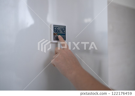 hand adjusting air conditioner button at 70 degree Fahrenheit in the apartment for comfortable hand adjusting air conditioner button at 70 degree Fahrenheit in the apartment for comfortable 122176459