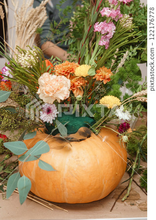 Flower arrangement in a pumpkin, autumn interior decor. Creating handmade autumn decor. Flower arrangement in a pumpkin, autumn interior decor. Creating handmade autumn decor. 122176778