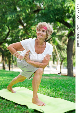Old lady standing in yoga pose outdoors 122177135