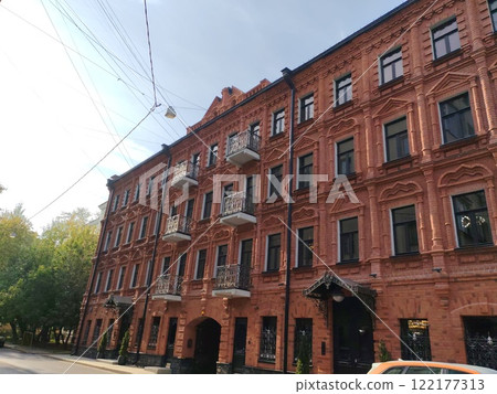 An ornate red brick facade with symmetrical windows, decorative balconies, and carved patterns. The photo captures the beauty and richness of historic architecture in a modern urban setting. An ornate red brick facade with symmetrical windows, decorative balconies, and carved patterns. The photo captures the beauty and richness of historic architecture in a modern urban setting. 122177313