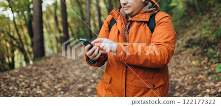 Young Caucasian 30s man backpacker with smartphone catching signal at wooden forest. Road trip, transport, travel, technology and people concept. High quality photo Young Caucasian 30s man backpacker with smartphone catching signal at wooden forest. Road trip, transport, travel, technology and people concept. High quality photo 122177322