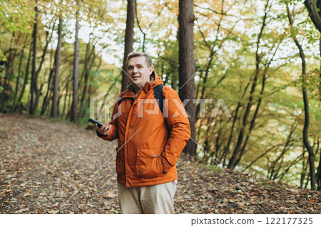 Young Caucasian 30s man backpacker with smartphone catching signal at wooden forest. Road trip, transport, travel, technology and people concept. High quality photo Young Caucasian 30s man backpacker with smartphone catching signal at wooden forest. Road trip, transport, travel, technology and people concept. High quality photo 122177325