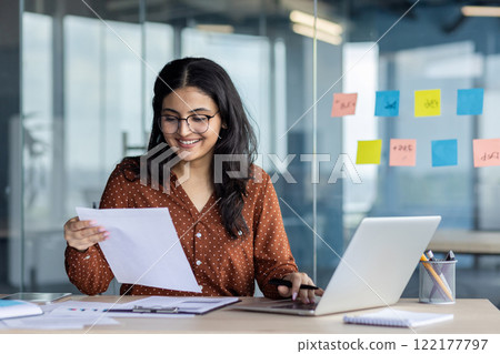 Paperwork office work, young successful latina woman working with documents and contracts inside office at workplace. Satisfied woman smiling checking, reports and tax forms. 122177797