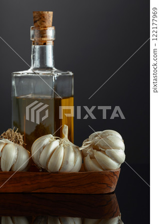 Garlic bulbs and bottle of vegetable oil on a black background. Garlic bulbs and bottle of vegetable oil on a black background. 122177969