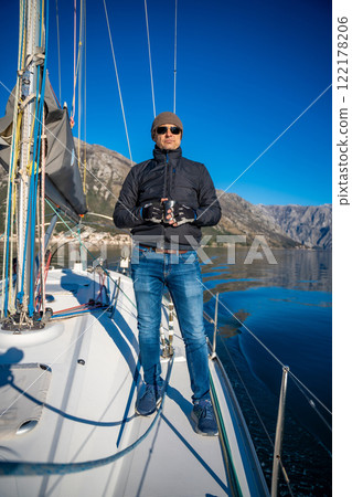 Man holding thermo mug on bow of the yacht during sailing in the morning in winter time in Adriatic sea, relaxation in yachting time Man holding thermo mug on bow of the yacht during sailing in the morning in winter time in Adriatic sea, relaxation in yachting time 122178206