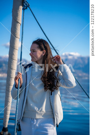 Portrait of young woman on bow of the yacht during sailing in the morning in winter time in Adriatic sea, yacht life and yachting concept Portrait of young woman on bow of the yacht during sailing in the morning in winter time in Adriatic sea, yacht life and yachting concept 122178210