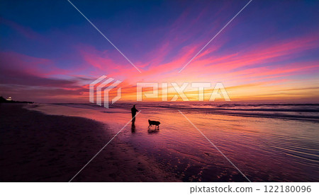 A person walking a dog on the beach during magic hour 122180096