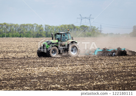 Tractor preparing soil for planting in rural farmland during spring Tractor preparing soil for planting in rural farmland during spring 122180111