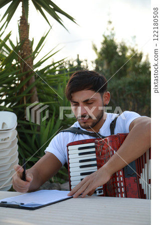 Man Studying Accordion And Watching On The Paper  122180508