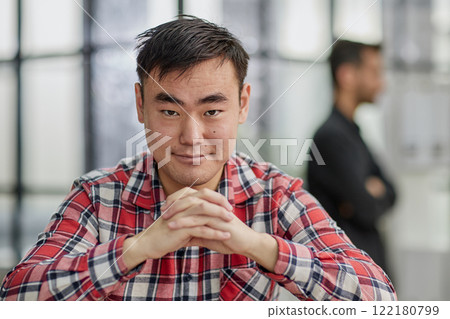 a successful businessman in a shirt sits at a table with folded hands. 122180799