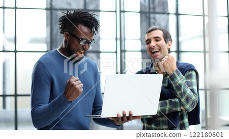 two male colleagues clench their fists looking happy and victorious two male colleagues clench their fists looking happy and victorious 122180801
