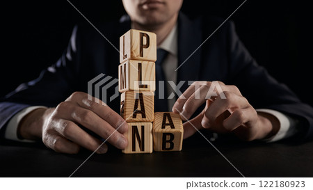 The hand turns the wooden cube and can't decide whether to change PLAN A to PLAN B. The hand turns the wooden cube and can't decide whether to change PLAN A to PLAN B. 122180923