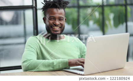Young african american business man sitting in loft office or cafe, working on new online IT startup project, using laptop 122180924