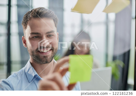 businessman is working on a project. Business man pointing at a note on the glass wall in the office. businessman is working on a project. Business man pointing at a note on the glass wall in the office. 122181236