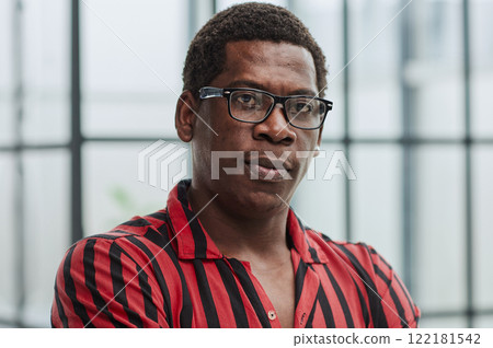 Portrait of confident african american businessman with glasses standing in office with crossed arms 122181542