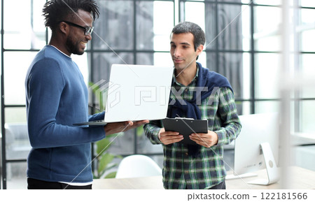 young business men standing together holding a laptop, discussing business 122181566
