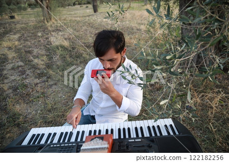 Boy Plays Music With Harmonica And Keyboard Among The Olive Trees Of Calabria 122182256