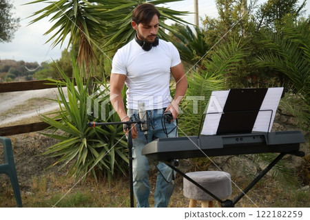 Musician Arranges His Keyboard For The Evening Performance In A Park 122182259