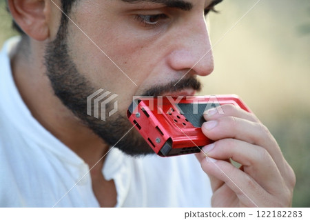 Boy Plays Music With Harmonica And Keyboard Among The Olive Trees Of Calabria Boy Plays Music With Harmonica And Keyboard Among The Olive Trees Of Calabria 122182283