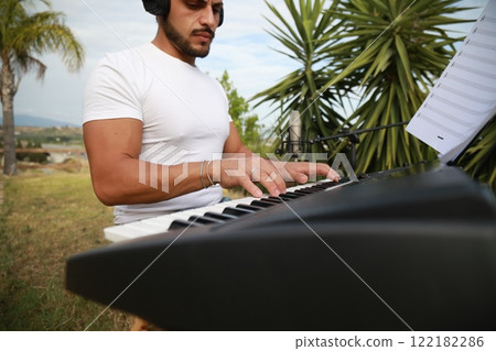 Boy Pianist Plays The Keyboard In An Outdoor Garden For A Private Party Boy Pianist Plays The Keyboard In An Outdoor Garden For A Private Party 122182286