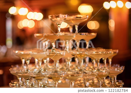Champagne glasses tower during large celebration with yellow luxury champagne.Macro.AI Generative Champagne glasses tower during large celebration with yellow luxury champagne.Macro.AI Generative 122182784