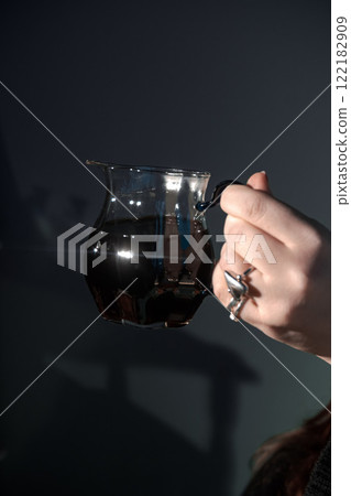 An Elegant Hand Gracefully Holding a Beautiful Glass Jug That is Filled with Dark, Rich Liquid An Elegant Hand Gracefully Holding a Beautiful Glass Jug That is Filled with Dark, Rich Liquid 122182909