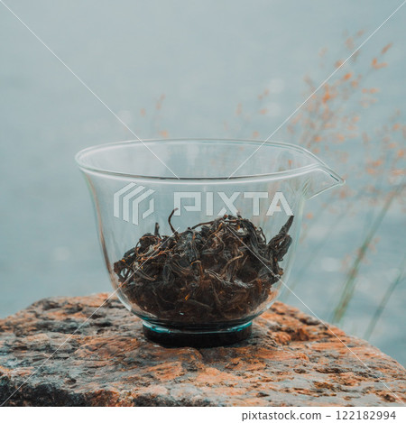A Collection of Dried Herbal Tea Leaves in a Clear Glass Bowl Set on Natural Stone Surface A Collection of Dried Herbal Tea Leaves in a Clear Glass Bowl Set on Natural Stone Surface 122182994