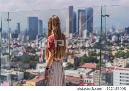Female tourist or businesswoman standing on a skyscraper rooftop with a panoramic view of Mexico City. Travel or international business in Mexico concept 122182998