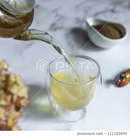 Pouring Herbal Tea into a designed Glass while adding Aromatic Spices for flavor and wellness 122183049