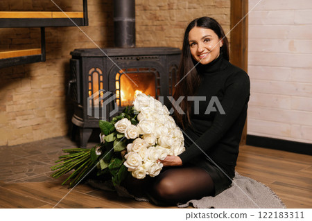 Woman holding large bouquet of white roses near fireplace Woman holding large bouquet of white roses near fireplace 122183311