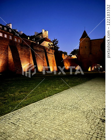 ancient castle of old red brick on a summer evening against the blue sky, a historic fortress from the 16th century for the defense of the city, Warsaw Barbican, Poland 122183332