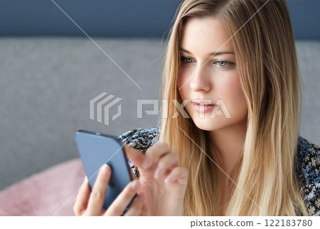 Woman with long blonde hair and blue eyes looking at her smartphone, online shopping, work from home lifestyle idea Woman with long blonde hair and blue eyes looking at her smartphone, online shopping, work from home lifestyle idea 122183780