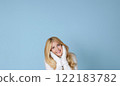 Winter portrait on blue background, happy blonde woman wearing warm mittens and knitted jumper, fashion and lifestyle idea 122183782