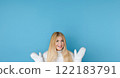 Winter portrait on blue background, happy blonde woman wearing warm mittens and knitted jumper, fashion and lifestyle idea 122183791
