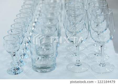 many different empty glass transparent glasses stand on the table in rows 122184479