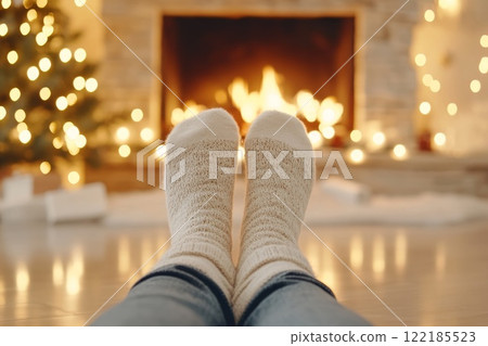 A childs hand holding a glitter-filled transparent Christmas ornament, blurred holiday lights in the background, festive scene 122185523
