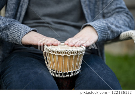 Closeup of hands playing a small djembe drum 122186152