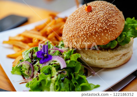 Delicious Gourmet Burger with Fresh Toppings and Crispy Golden Fries Served on a Beautiful Plate Delicious Gourmet Burger with Fresh Toppings and Crispy Golden Fries Served on a Beautiful Plate 122186352