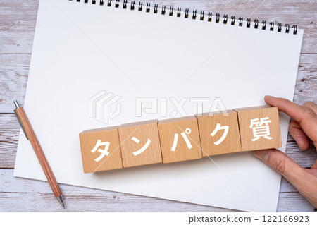 Blocks with protein letters, notebook and hand 122186923