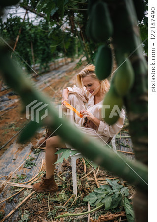 Woman harvesting fruits in a greenhouse surrounded by plants in the afternoon 122187490