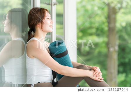 一個帶著瑜珈墊的瑜珈教練的女人，一個做瑜珈和普拉提的女人 122187944