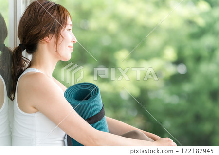 一個帶著瑜珈墊的瑜珈教練的女人，一個做瑜珈和普拉提的女人 122187945