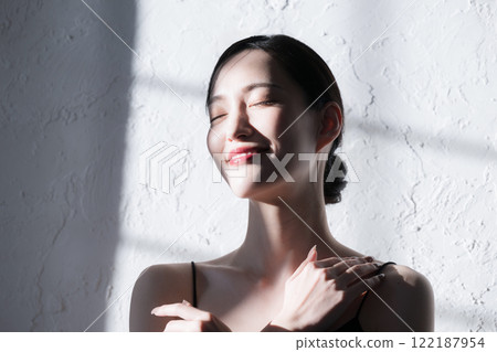 一位年輕女性在陽光下做皮膚護理,輪廓美麗,亮點突出 一位年輕女性在陽光下做皮膚護理,輪廓美麗,亮點突出 122187954