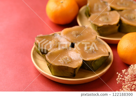Sticky rice cake (Nian Gao), Chinese New Year cake and orange fruit on red background Sticky rice cake (Nian Gao), Chinese New Year cake and orange fruit on red background 122188300