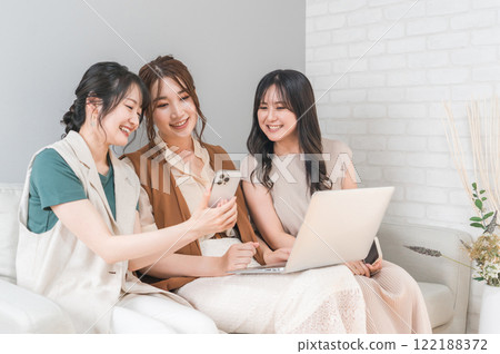 Women, friends, mom friends, and colleagues who use smartphones and laptops together at home 122188372